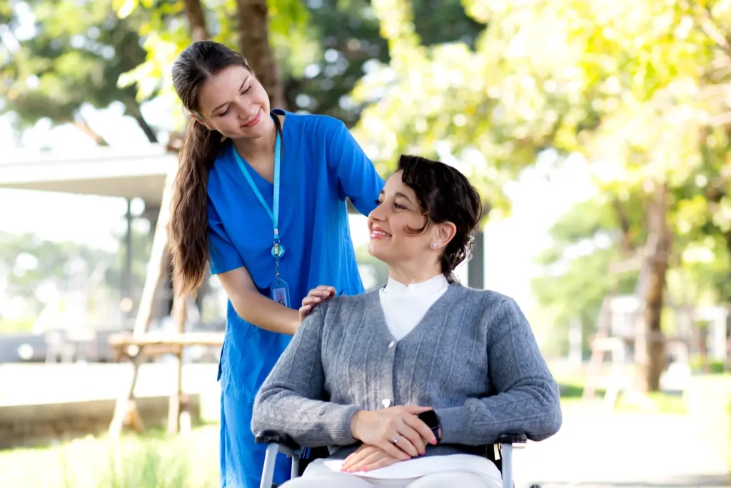 nurse helping a women on wheel chair in a park